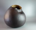 Large sculptural black clay vessel with rounded form, indented surface and irregular opening