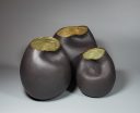 Three asymmetrical black clay ceramic vessels with softly contoured surfaces and glazed interiors